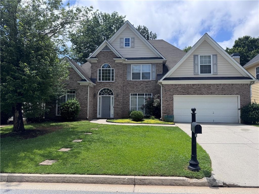 Traditional home with driveway, a garage, brick siding, and a front yard