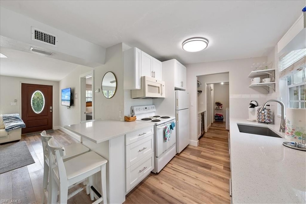 Kitchen featuring open shelves, a sink, white appl