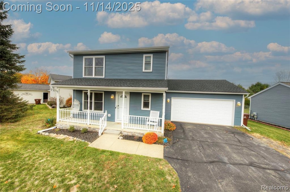 Traditional-style house with a porch, a front lawn, a garage, a shingled roof, and asphalt driveway