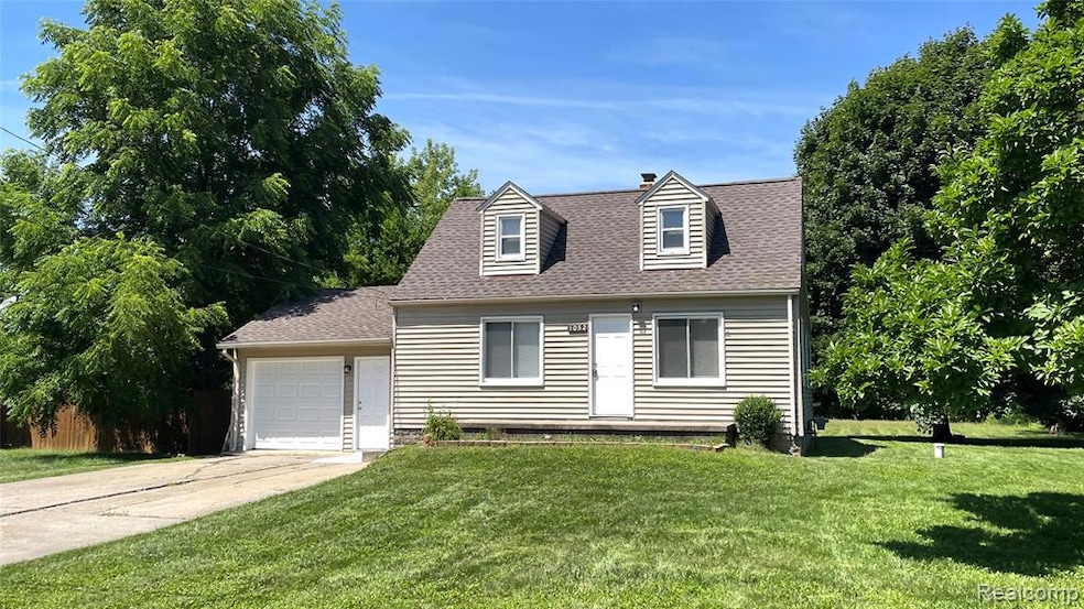 New england style home with a front lawn, a shingled roof, driveway, and a garage