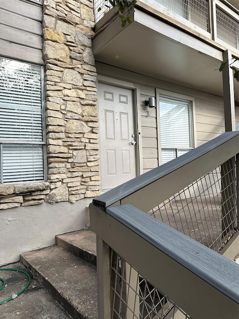 Doorway to property with stone siding and a balco