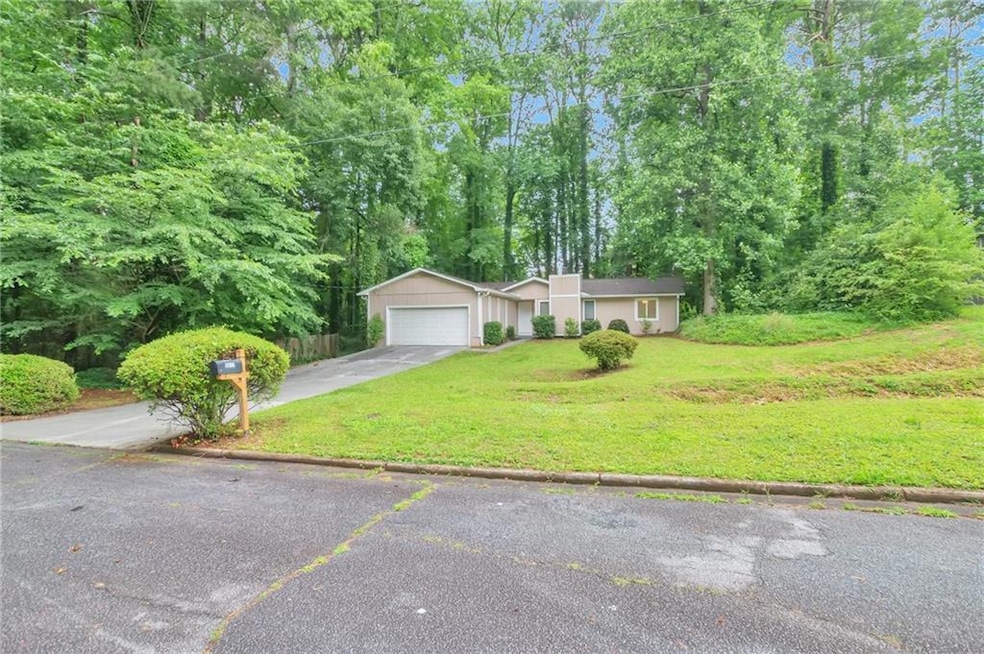 View of front of property featuring a front yard, driveway, and a garage