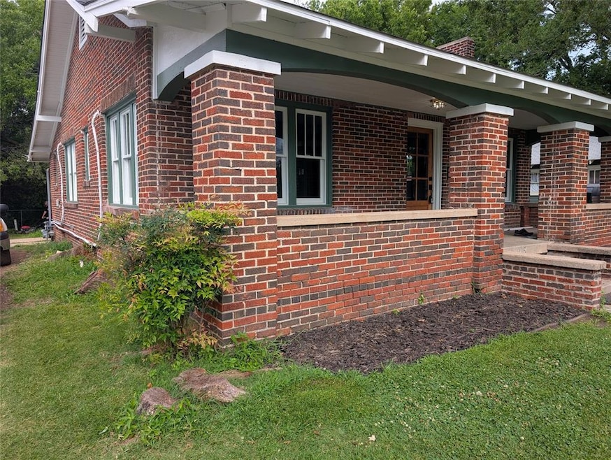 View of property exterior featuring brick siding, a chimney, and a lawn