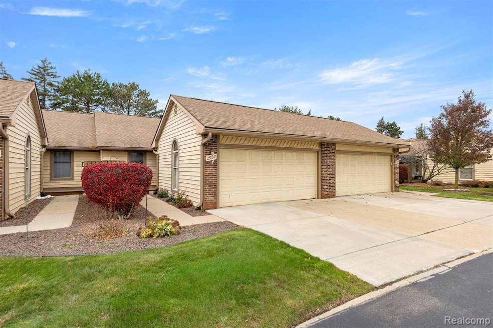 View of front facade featuring a shingled roof, brick siding, concrete driveway, and a front yard