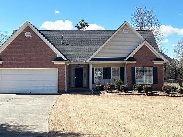 View of front of home featuring concrete driveway, a front lawn, and brick siding