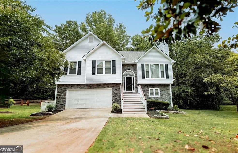 Bi-level home featuring stone siding, a garage, driveway, and a chimney