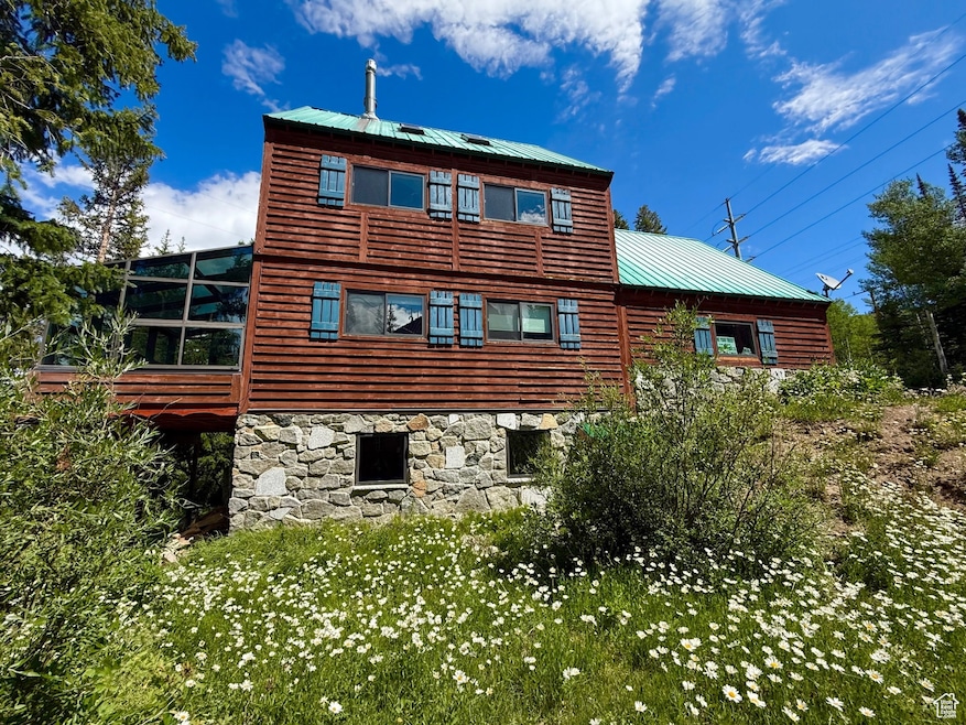 Rear view of house with a metal roof and stone siding