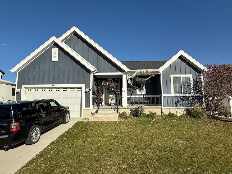 View of front of property with board and batten siding, a garage, a front lawn, a porch, and concrete driveway
