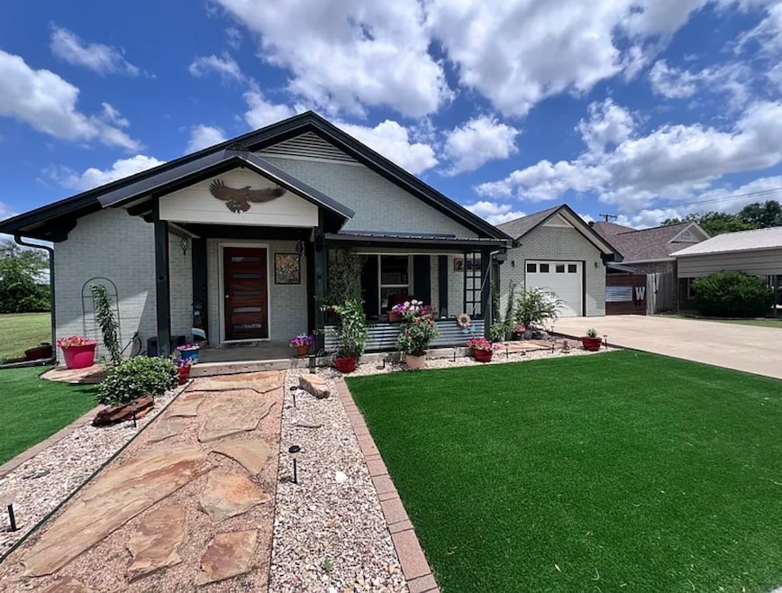 Single story home featuring covered porch, a front lawn, brick siding, and driveway