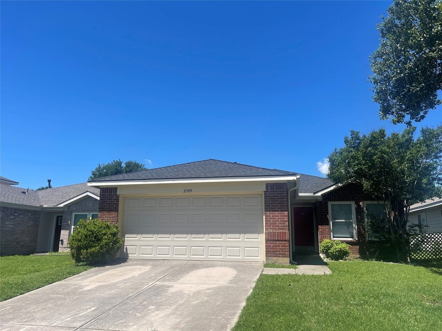 Single story home with brick siding, a garage, a front yard, and concrete driveway