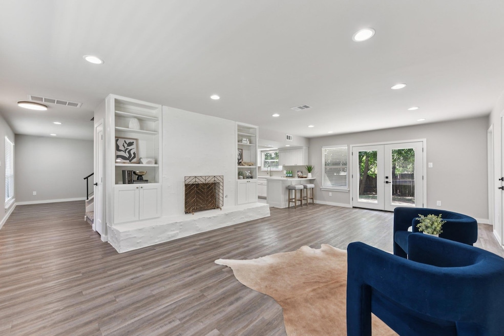 The spacious main living area features updated flooring, recessed lighting, and a redesigned fireplace with built-in shelving, creating an inviting central hub.