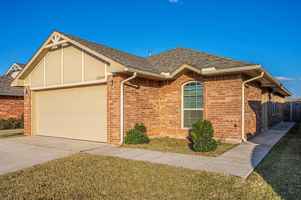 View of front of home featuring a garage, roof with shingles, driveway, and brick siding