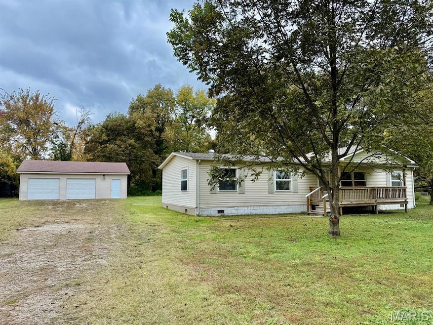 View of front of home with crawl space, a front yard, an outbuilding, a detached garage, and a wooden deck
