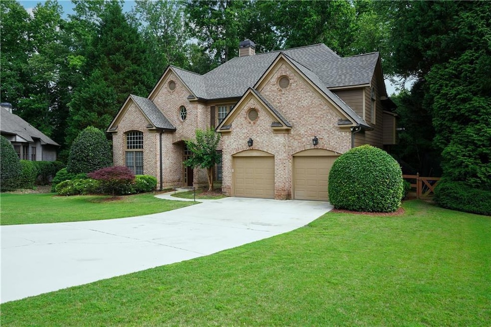 View of front of property with concrete driveway, brick siding, roof with shingles, a front lawn, and a chimney