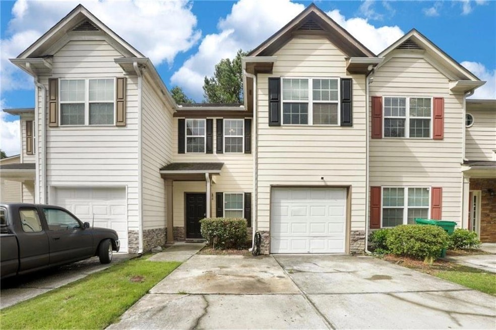 Multi unit property featuring a garage, stone siding, and driveway