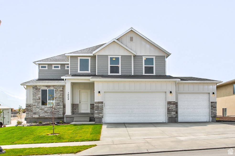 View of front facade featuring stone siding, board and batten siding, driveway, and roof with shingles