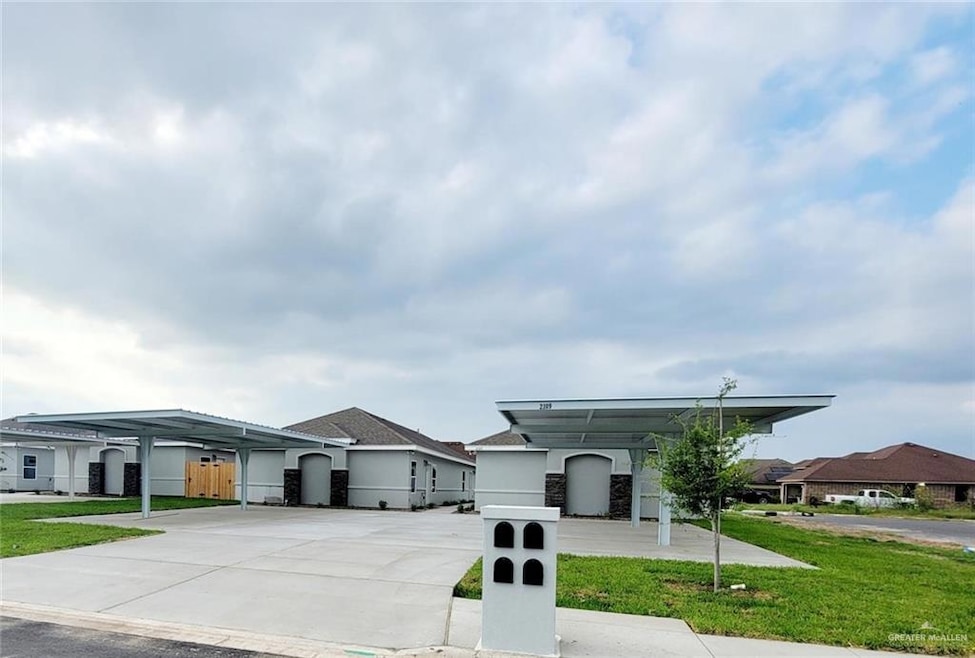 View of front of house featuring concrete driveway, fence, a front yard, and stucco siding