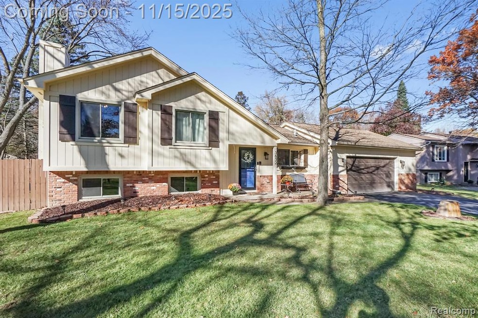 Tri-level home featuring brick siding, a chimney, an attached garage, and driveway