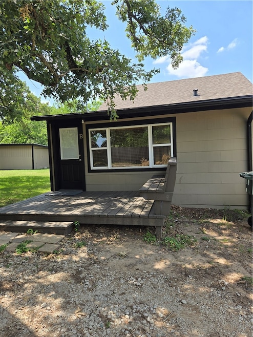 Back of house with a deck and a shingled roof