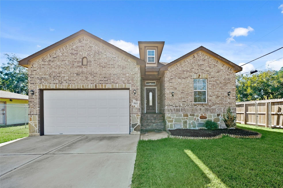 Beautiful traditional brick and stone-accented front elevation of the home featuring a two-car garage and manicured lawn.