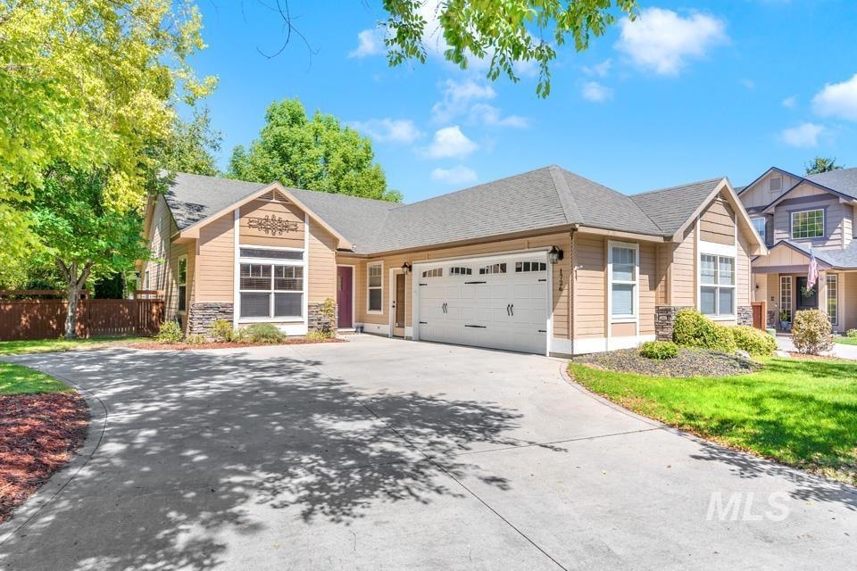 Craftsman-style home featuring driveway, stone siding, a garage, and roof with shingles