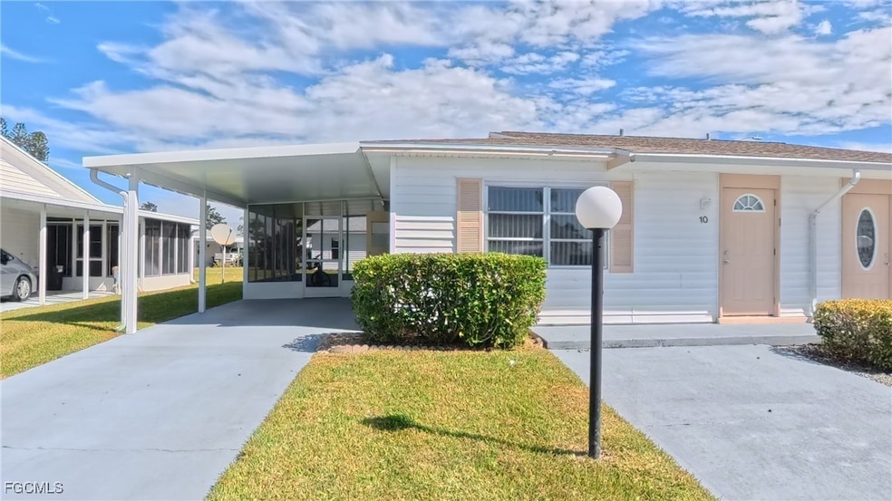 View of front of home featuring concrete driveway, a carport, and a front yard