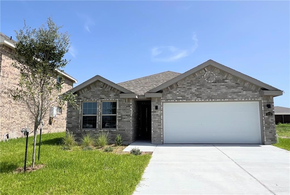 Single story home featuring brick siding, a garage, driveway, roof with shingles, and a front yard
