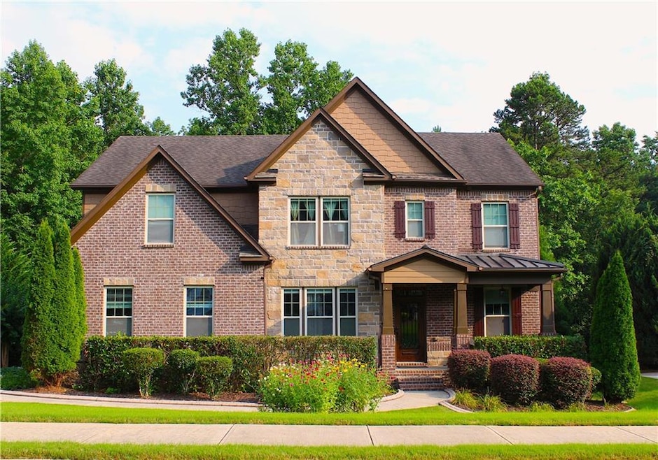 Craftsman-style house with brick siding, stone siding, a shingled roof, and covered porch