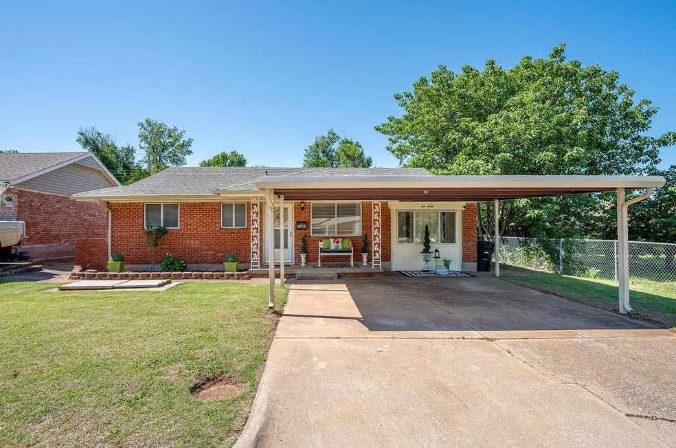 View of front of house with brick siding, a carport, a porch, and driveway