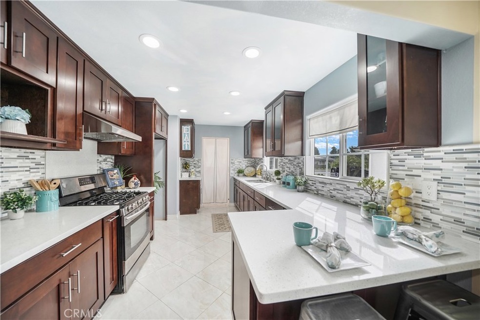 Gorgeous Completely Remodeled Kitchen with Quartz Counters, Glass Mosaic Tile Backsplash, Custom Cabinetry with Glass Display Panels, Stainless Appliances, Stainless Sinks, Recessed Lighting, Tile Flooring, & Breakfast Bar