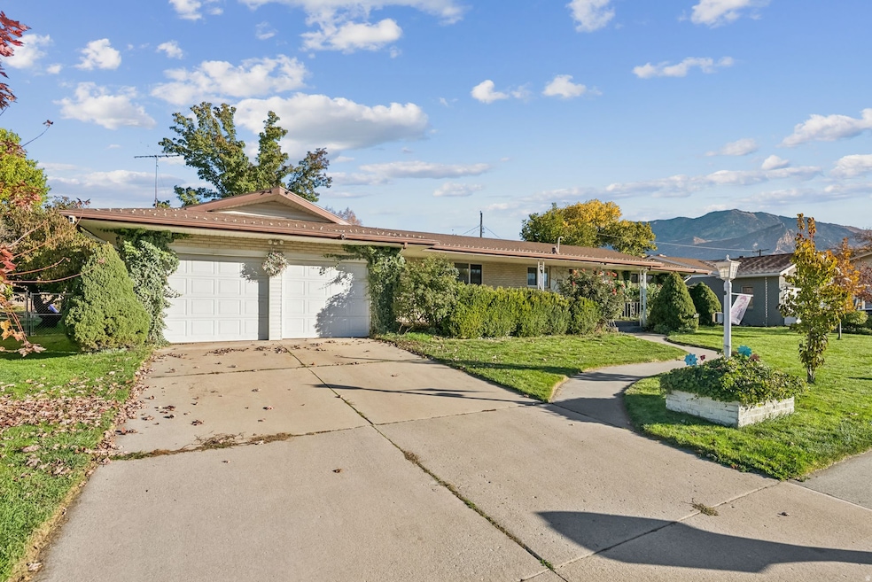 Ranch-style house featuring driveway, a mountain view, a garage, and a front lawn