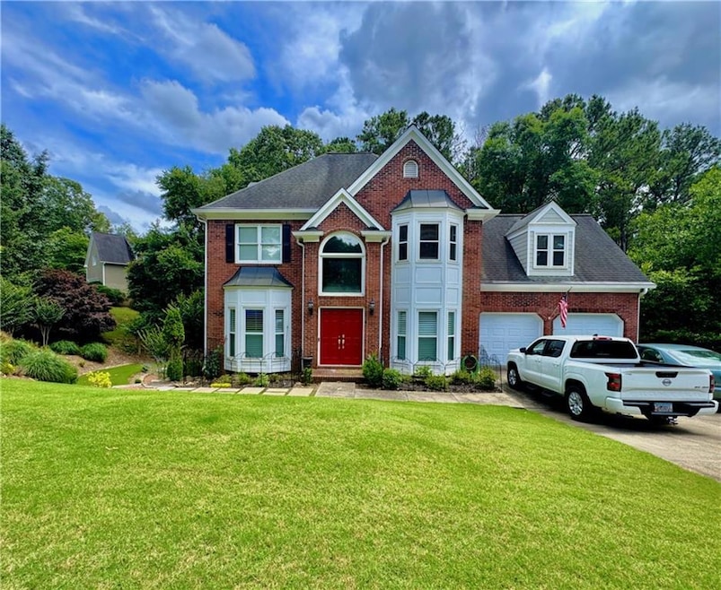 View of front of property featuring brick siding, a front yard, a garage, and concrete driveway