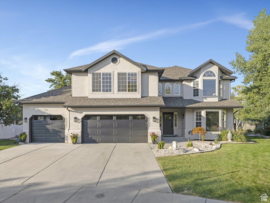 Traditional home featuring stucco siding, a front lawn, driveway, a porch, and an attached garage