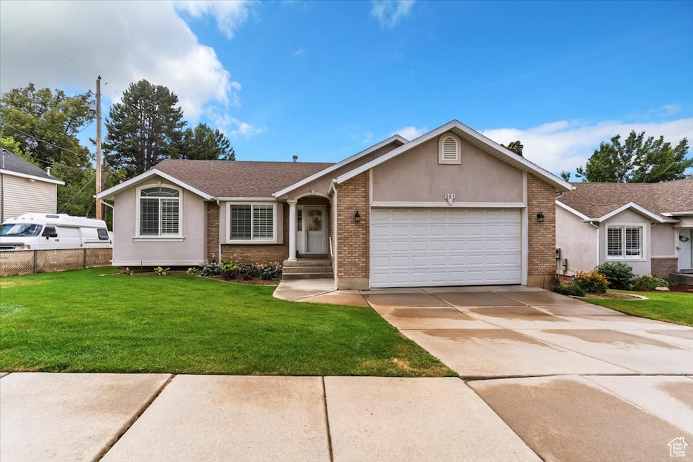 Single story home with an attached garage, brick siding, concrete driveway, a front yard, and stucco siding