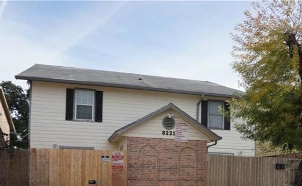 View of front of home with brick siding and fence
