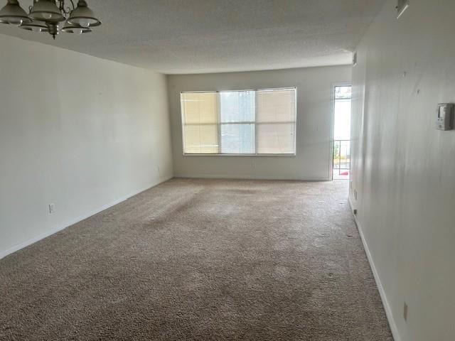 Spare room featuring carpet and a chandelier