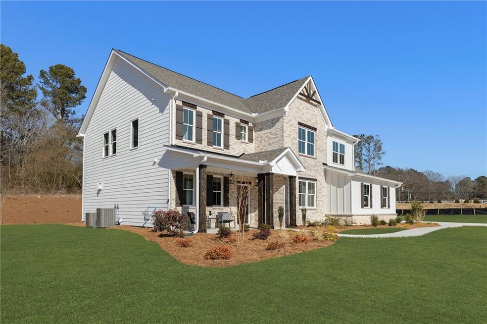 View of front facade with stone siding, a front yard, central AC unit, a porch, and a shingled roof
