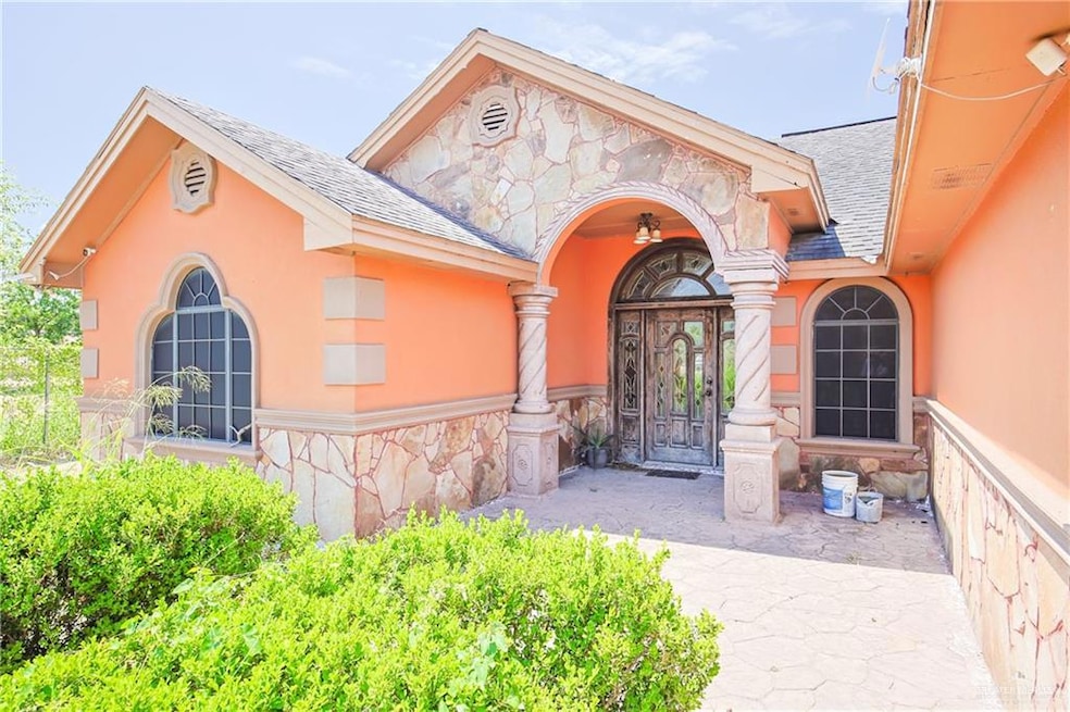 Doorway to property featuring roof with shingles, stone siding, and stucco siding