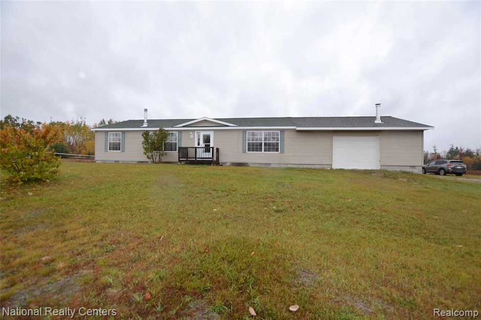 View of front of home featuring a front yard, a deck, crawl space, and a garage