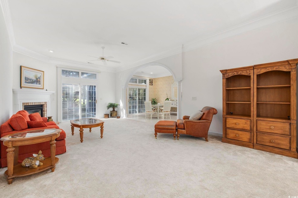 Carpeted living room with ornate columns, crown mo