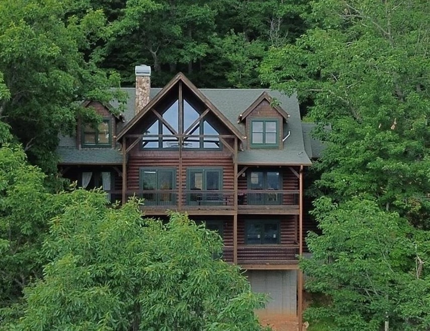 Rear view of property featuring a balcony, a chimney, and log siding
