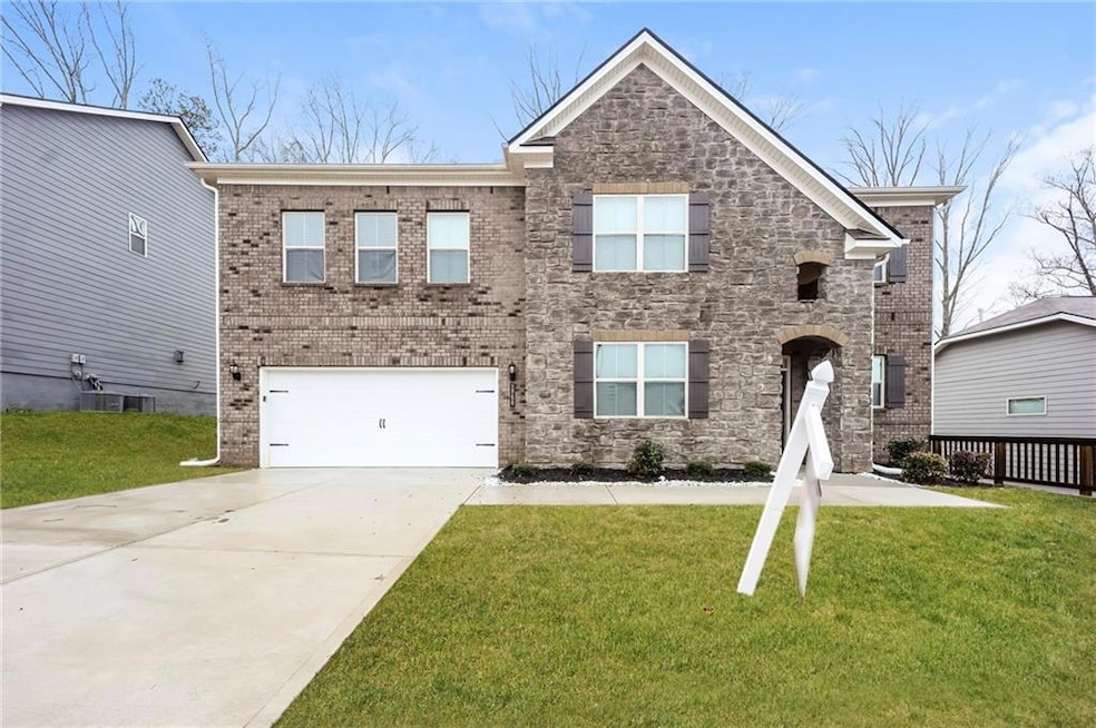 View of front facade featuring a garage, a front lawn, concrete driveway, and brick siding