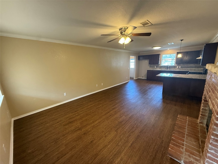 Unfurnished living room with crown molding, dark wood-style floors, a textured ceiling, and a ceiling fan