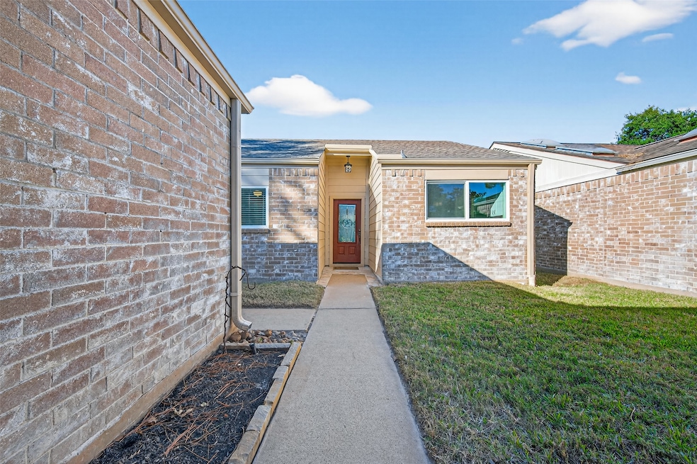 A welcoming walkway leads to the front door, framed by brick walls and a neatly kept courtyard that creates a private and inviting entryway.