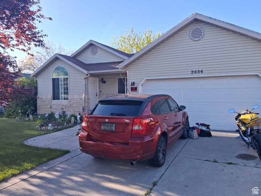 Single story home featuring a garage, driveway, a front lawn, and brick siding