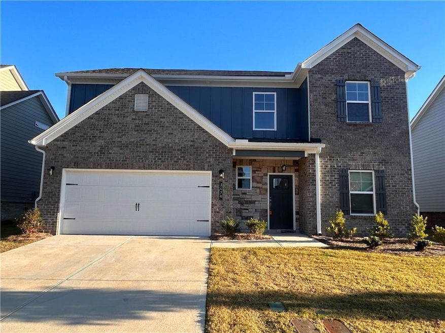 View of front facade with a garage, driveway, and board and batten siding