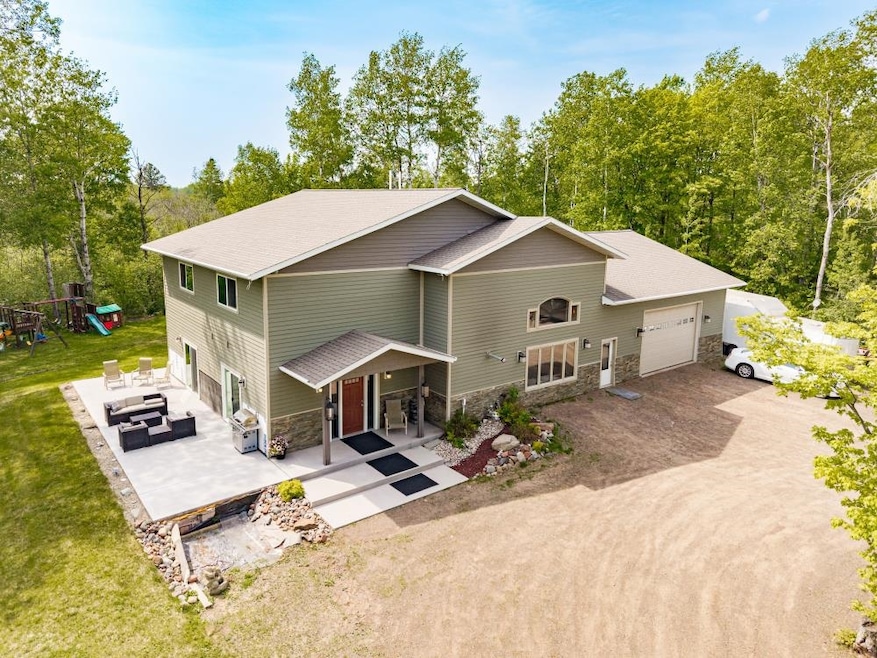View of front of property with stone siding, a garage, an outdoor living space, a front lawn, and dirt driveway