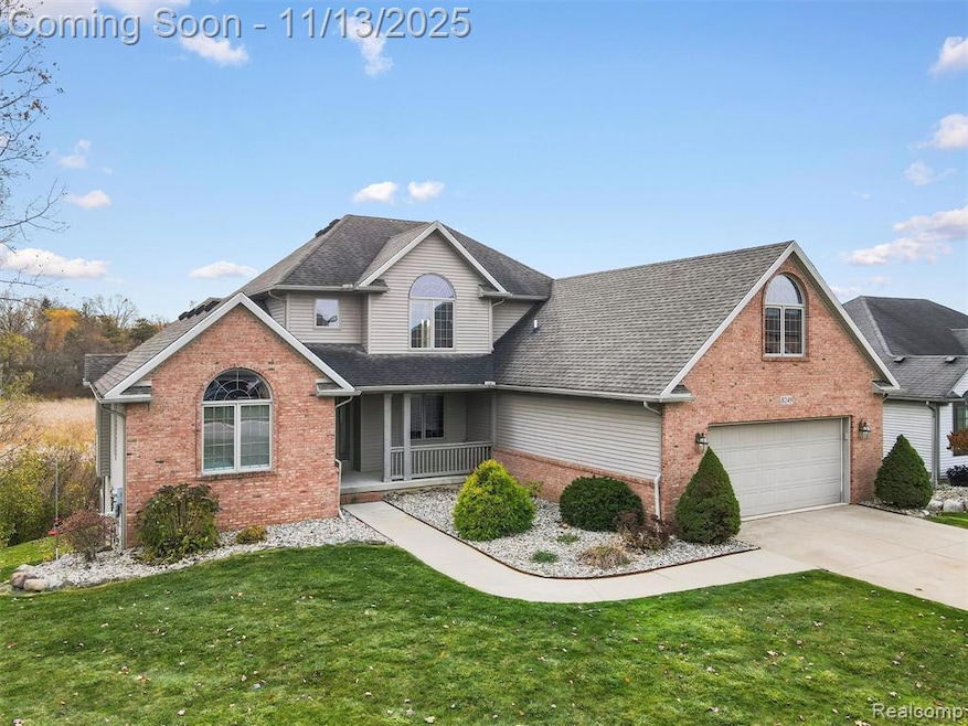 Traditional-style home with a porch, brick siding, and a front lawn