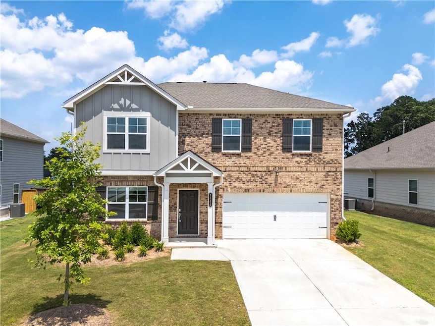 Craftsman house featuring board and batten siding, a garage, brick siding, a front yard, and driveway