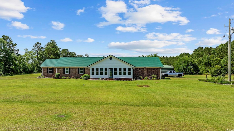 View of front of property with a front lawn, metal roof, and brick siding